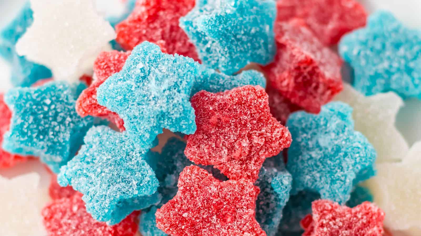 Close-up of star-shaped gummy candies in red, blue, and white, coated with sugar.