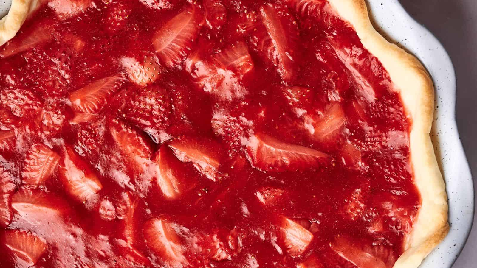 Close-up of a strawberry pizza featuring a thin crust topped with a layer of strawberry sauce and sliced strawberries, evoking the delightful appearance of a strawberry pie with its vibrant red color.