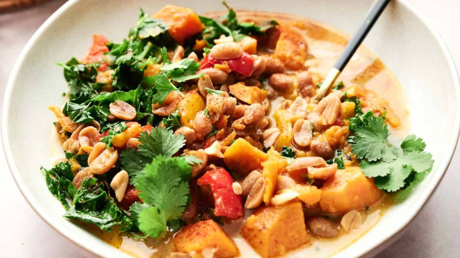 A bowl of Thai peanut curry with carrots, beans and kale.