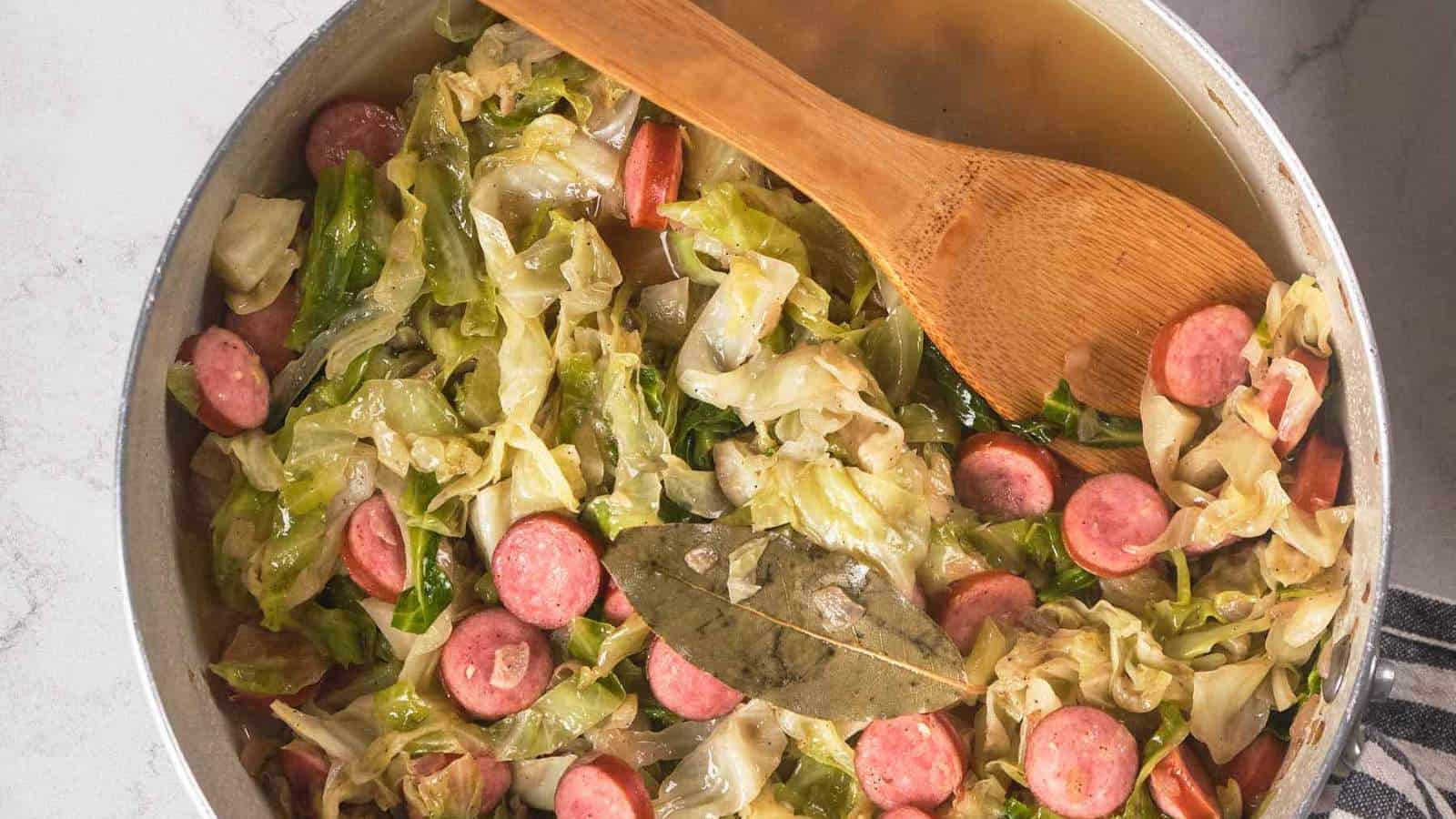 A pot of cabbage and sausage with a wooden spoon.