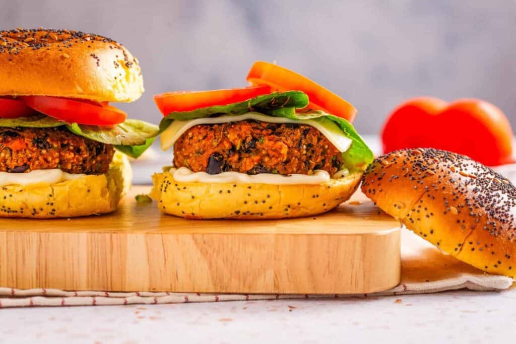 An image of black bean quinoa burger on a cutting board with the top bun on the side.
