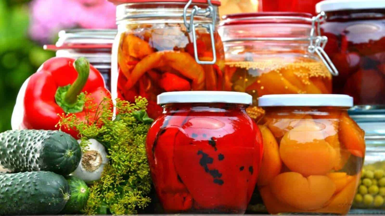 A variety of pickled fruits and vegetables in glass jars.