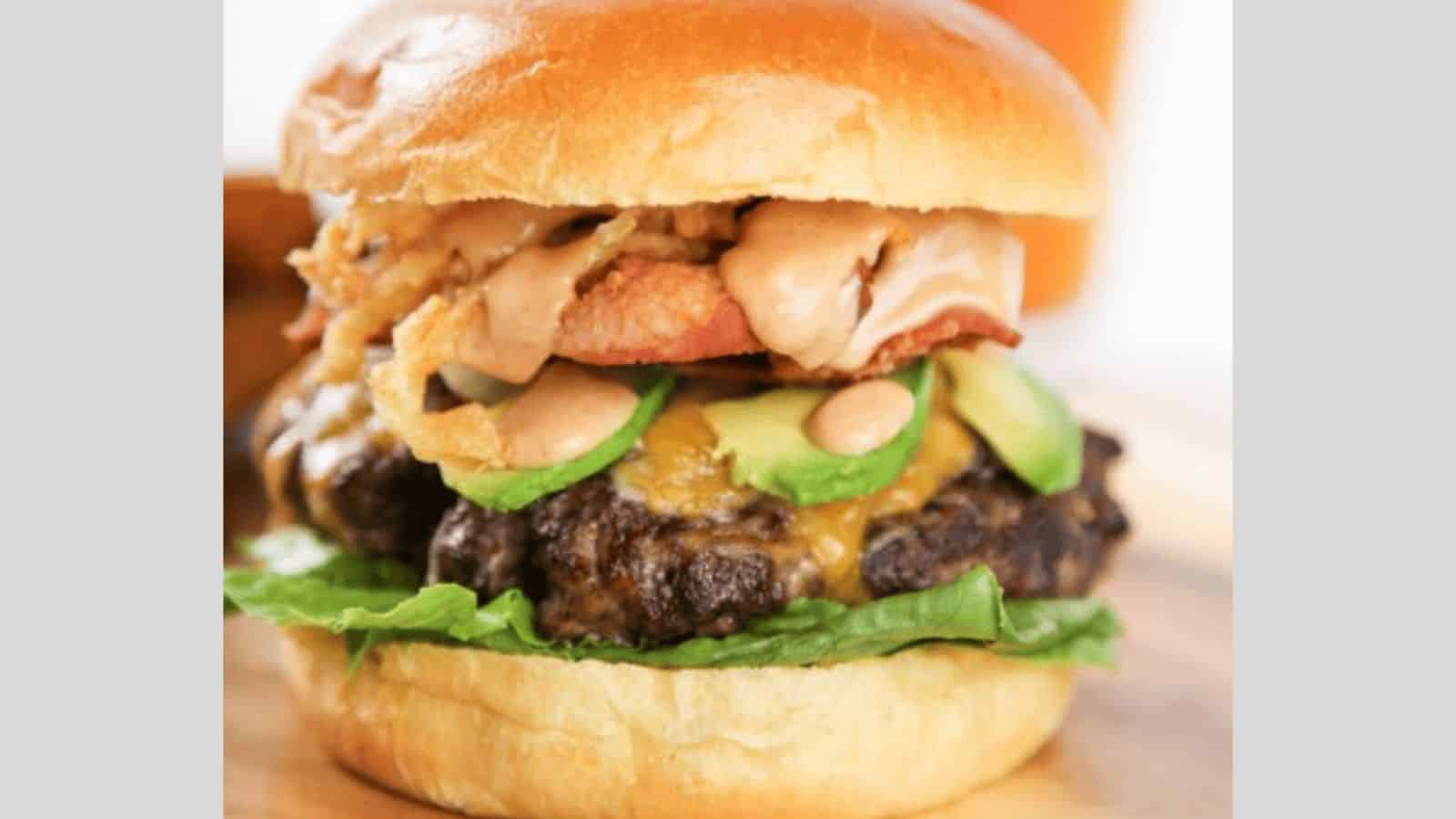 A cheeseburger topped with avocado, crispy onion strings, and a secret burger sauce.