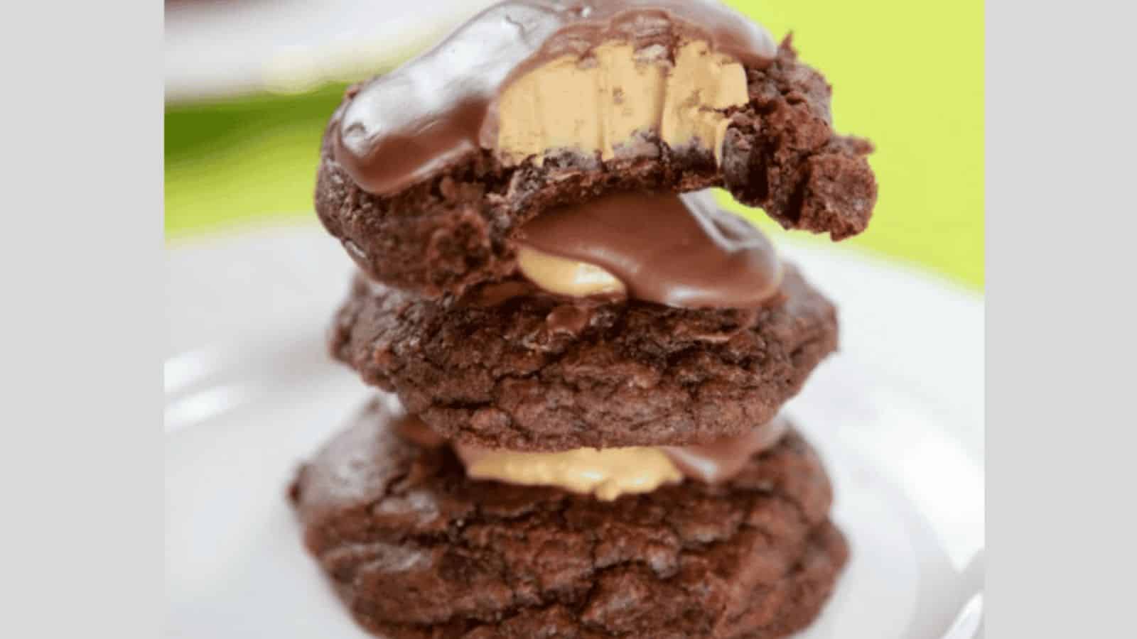 Three stacked brownie cookies topped with chocolate and peanut butter.