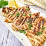 Four pieces of Ninja Woodfire Grill Lemon-Herb Chicken served on a white rectangular plate.