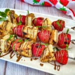 Three pieces of Grilled Strawberry Shortcake Skewers on a white plate.