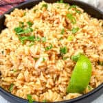 Mexican Rice with a slice of lime on a black bowl.