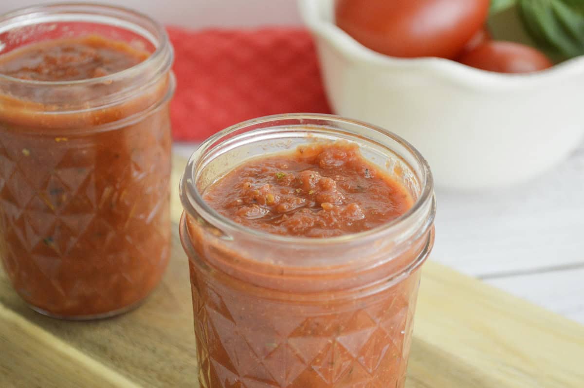 Two jars of tomato sauce on a cutting board.