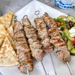 Ninja Woodfire Pork Souvlaki with Horiatiki Salad and pita bread on a white plate.