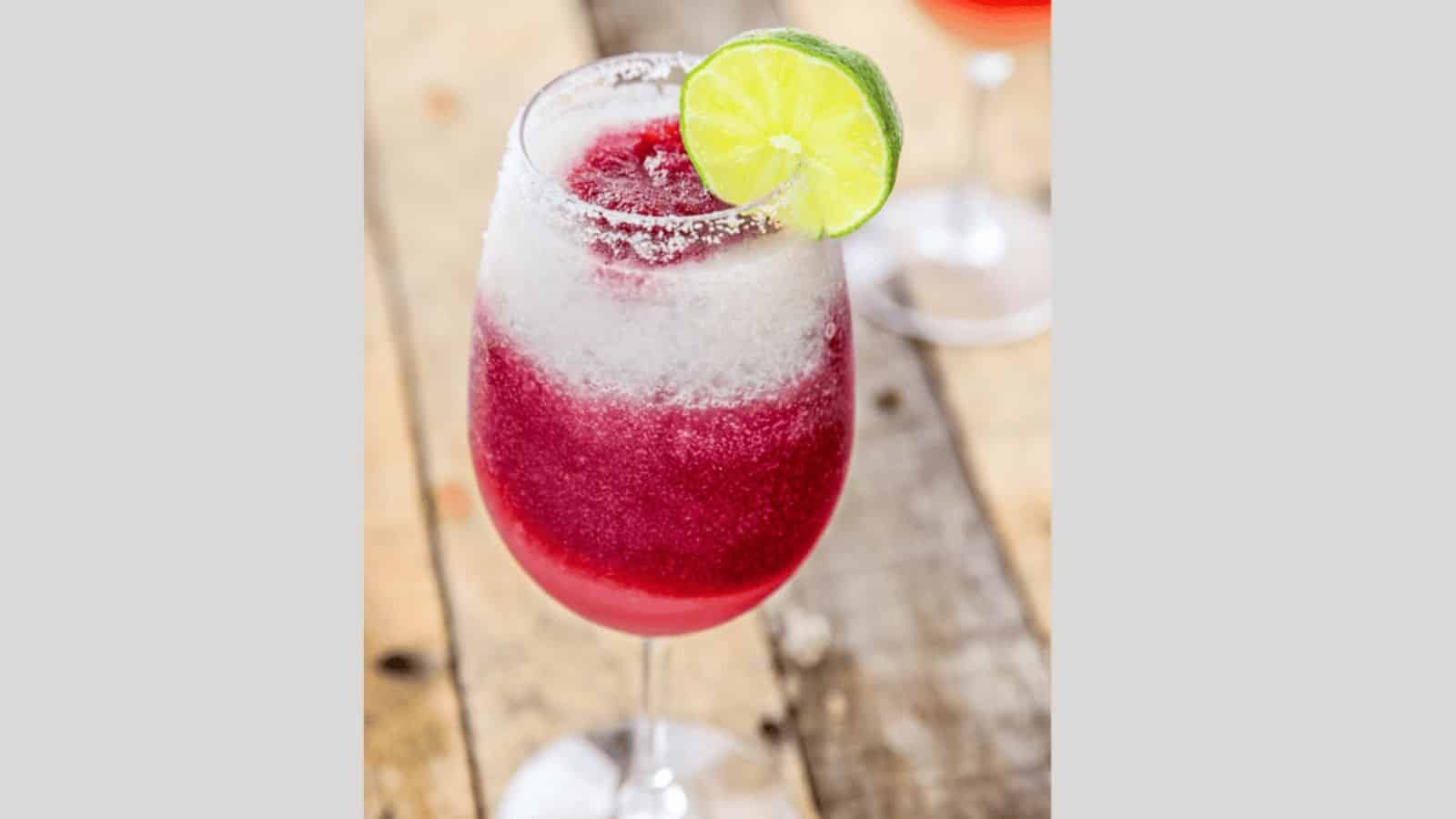 A red wine and lime maragrita swirled sangria margarita garnished with a lime wedge.