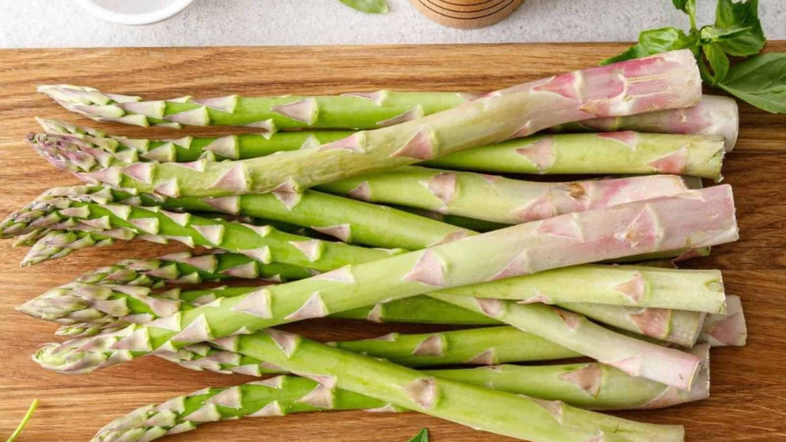 A slow cooker filled with fresh asparagus and seasonings.