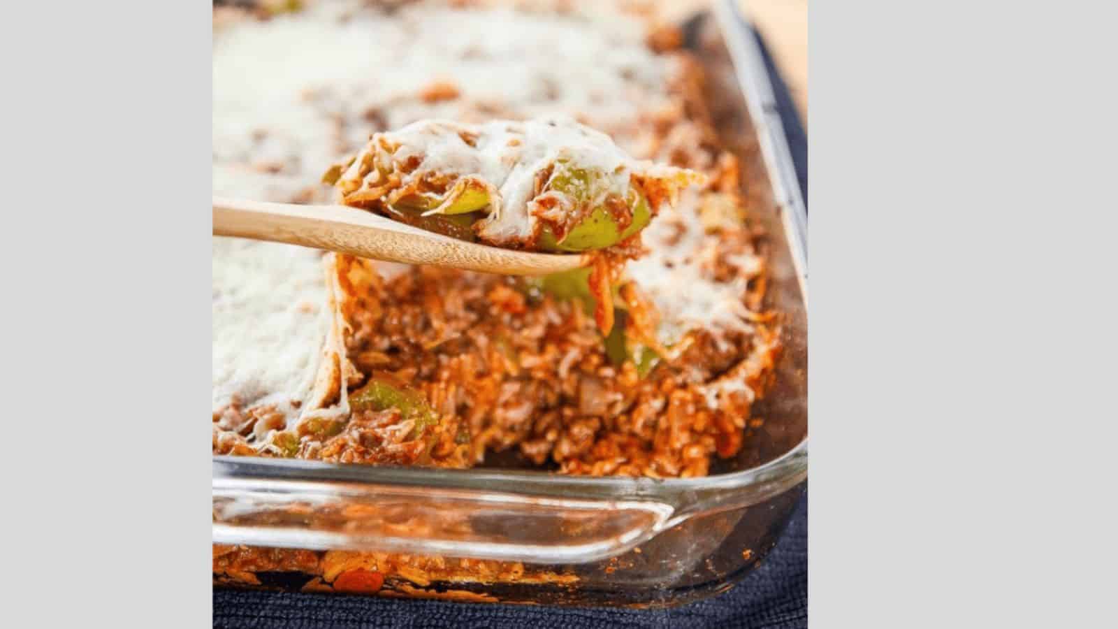 A spoon lifting out stuffed pepper casserole topped with mozzarella cheese.