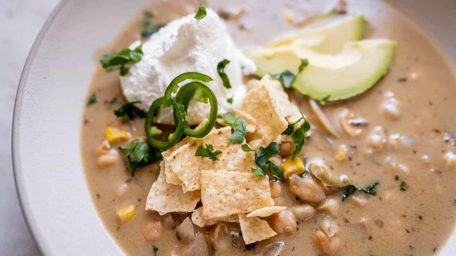 Bowl of vegan white chickpea chili topped with avocado and cilantro.