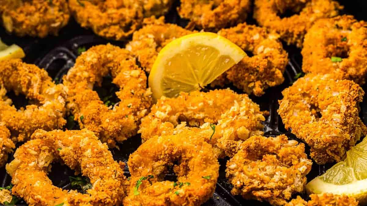 Golden brown calamari in an air fryer basket, ready to be served.