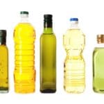 Five bottles of cooking oil with varying shapes and sizes are arranged in a row against a white background.