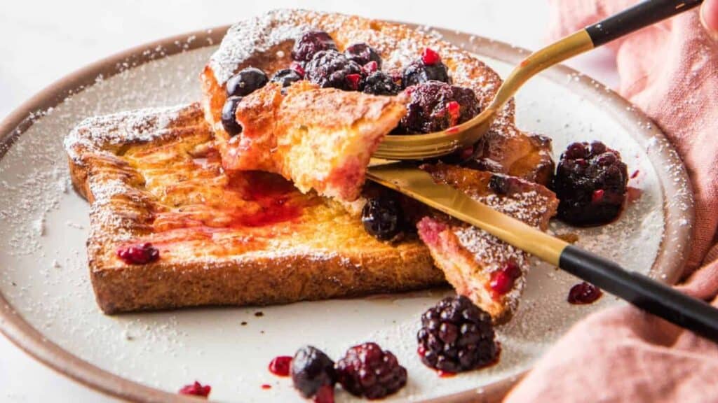 French toast on a plate with berries on top. 