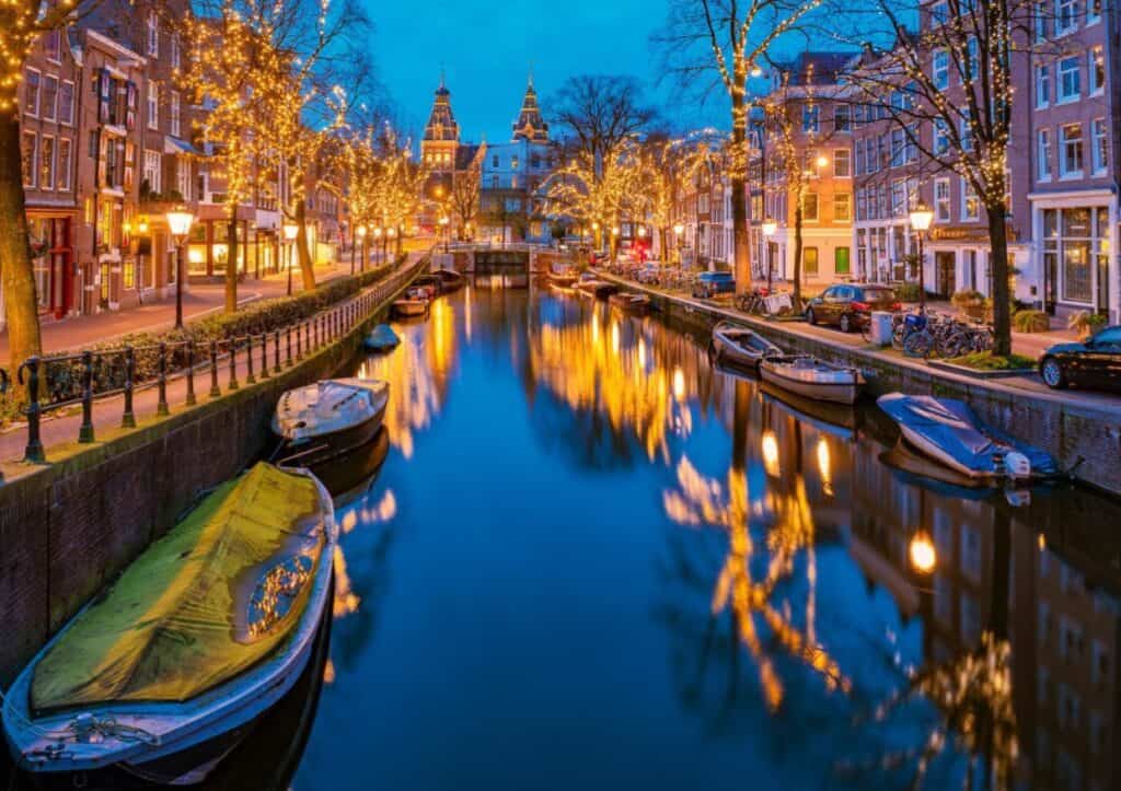 A Dutch canal lined with tall houses and decorated with lights for the holidays.