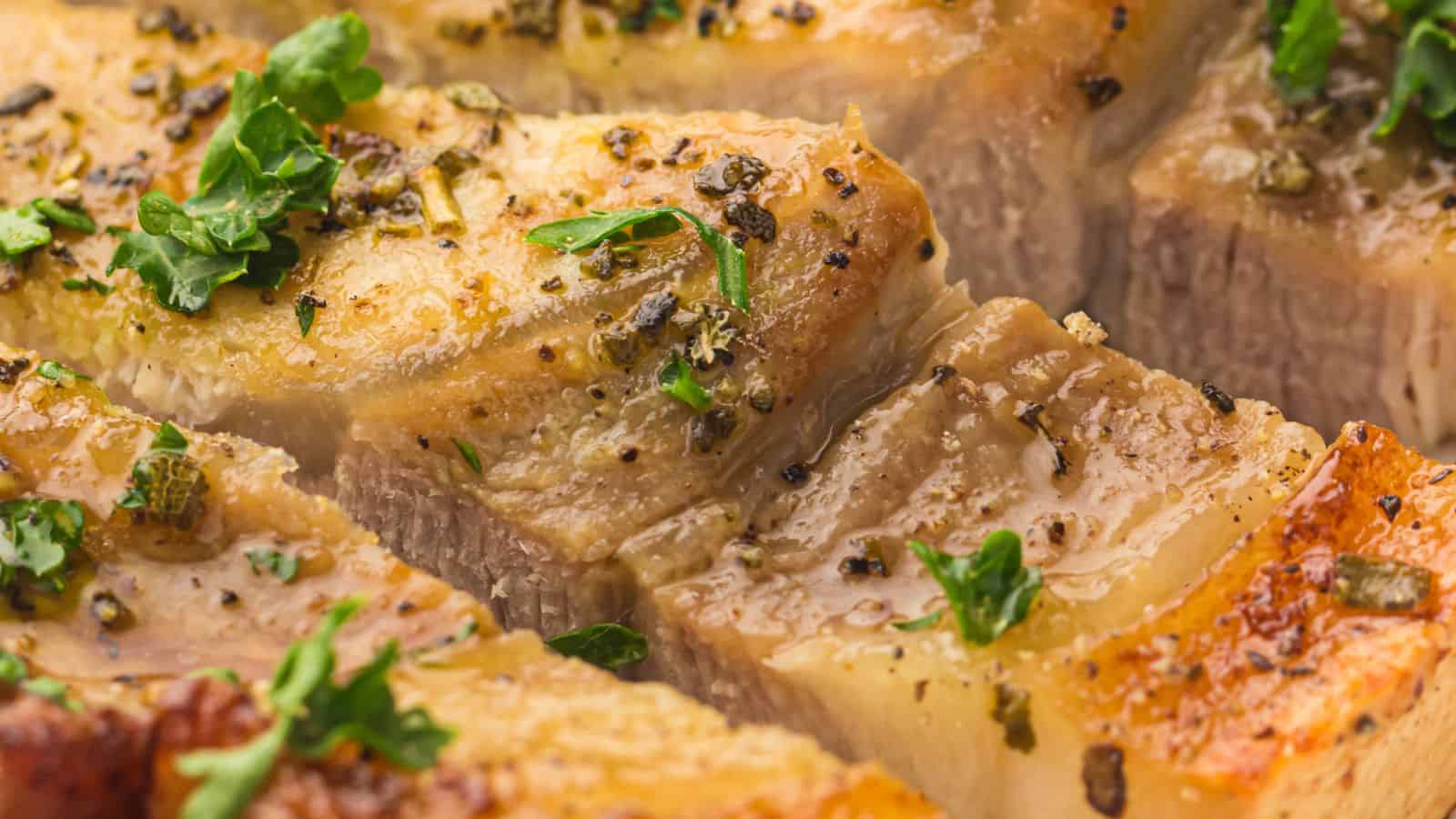 Close-up of seasoned and cooked air fryer pork chops, garnished with herbs and cracked black pepper.