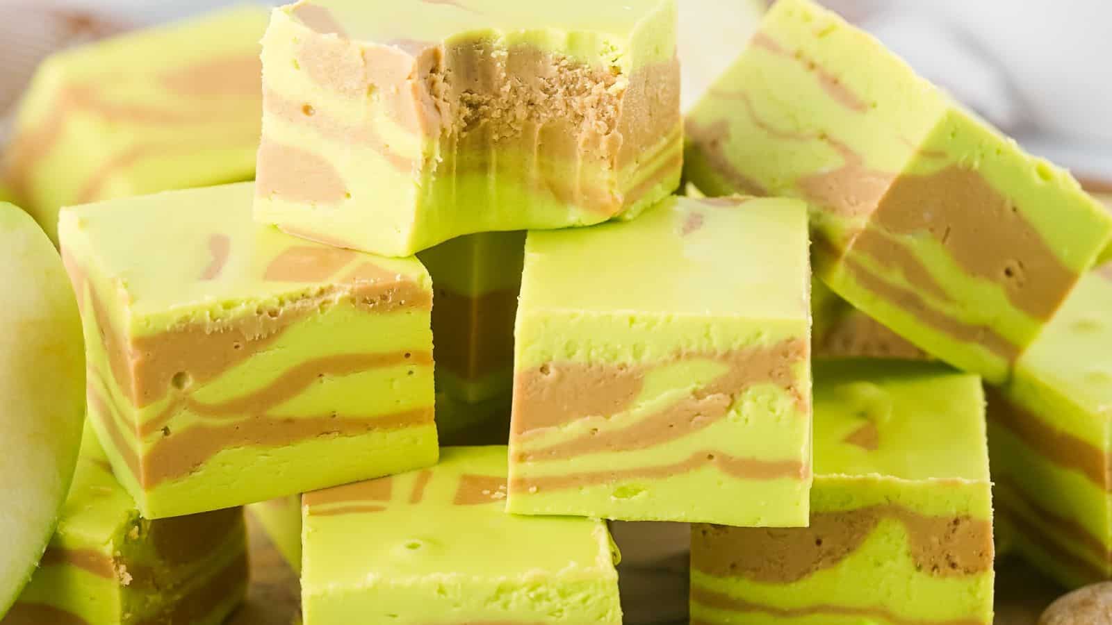 A stack of green and brown swirled fudge cubes. The top cube has a bite taken out of it.