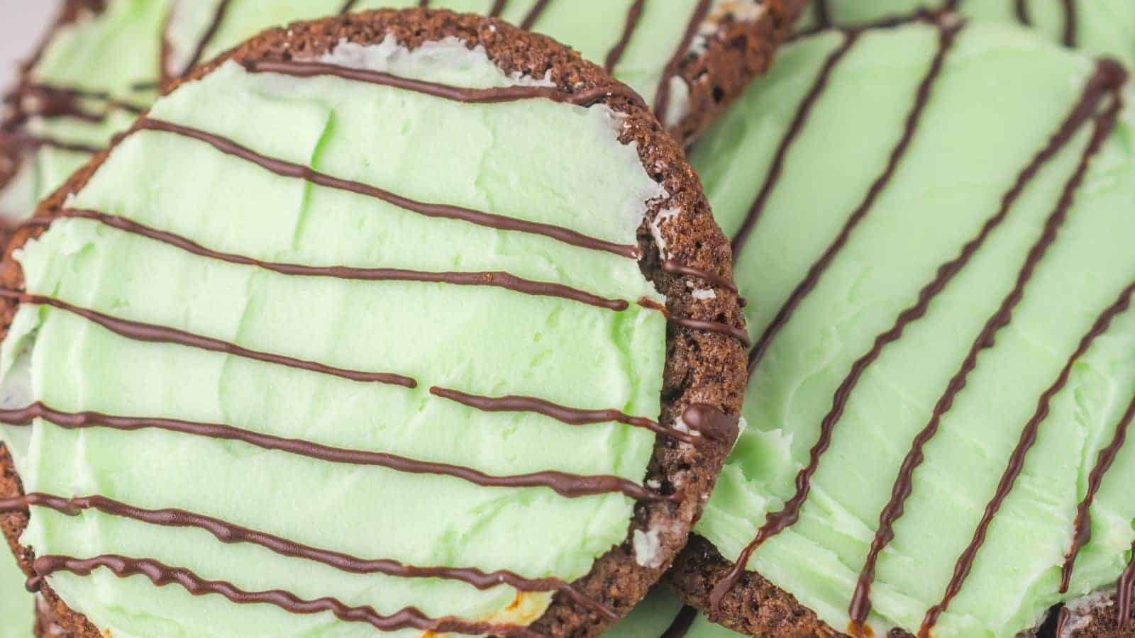 Close-up of Thin Mint Chocolate Cookies with green frosting and chocolate drizzle on top.