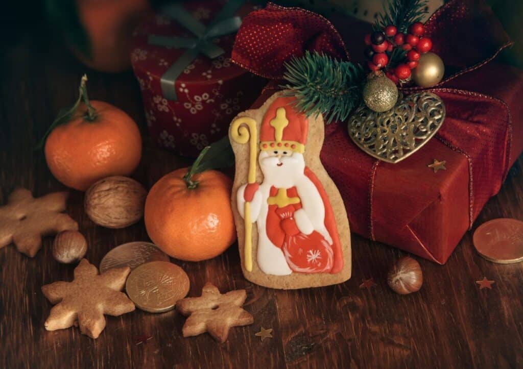 A cookie decorated with Sinterklaas next to wrapped gifts and chocolate coins.