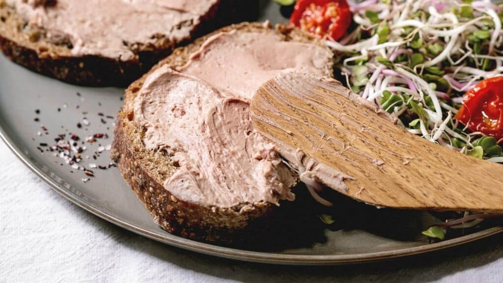 A plate with a piece of bread spread with chicken liver pate.