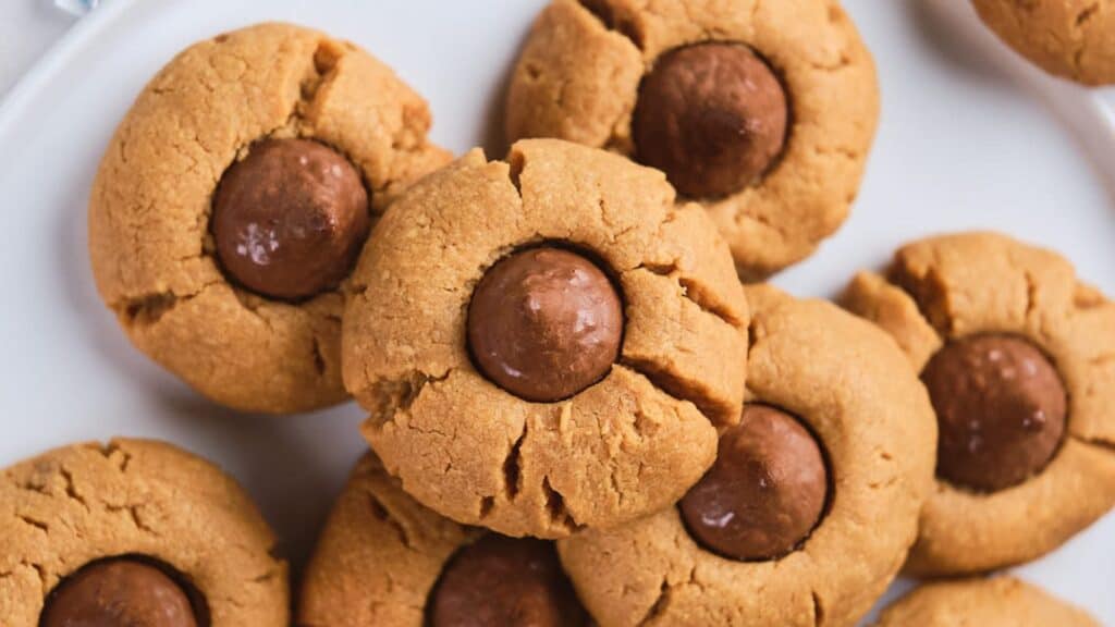A plate of peanut butter cookies with chocolate centers. The cookies are golden brown and round with slightly cracked tops.