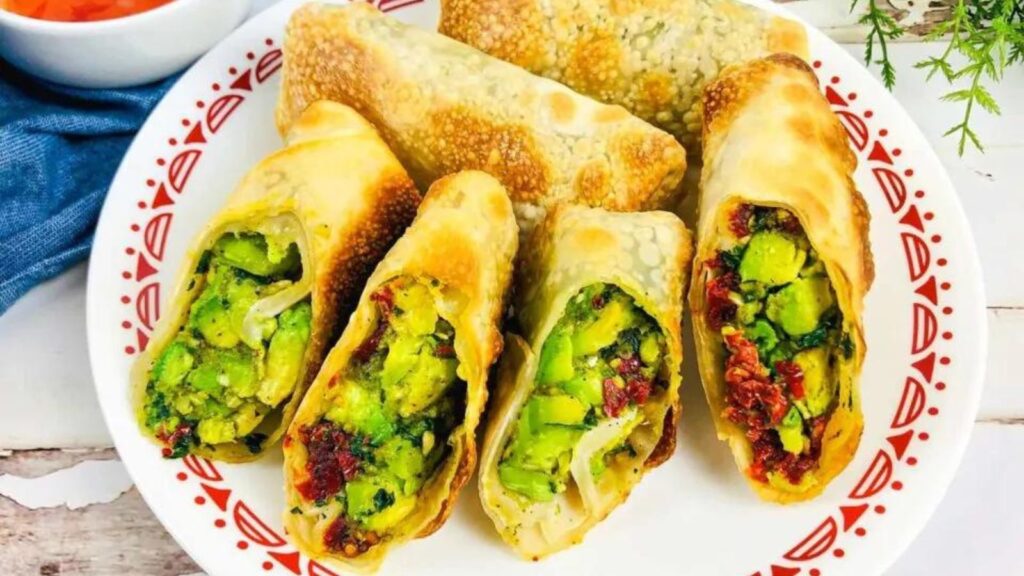A plate contains Air Fryer Avocado Egg Rolls served on a red patterned plate.
