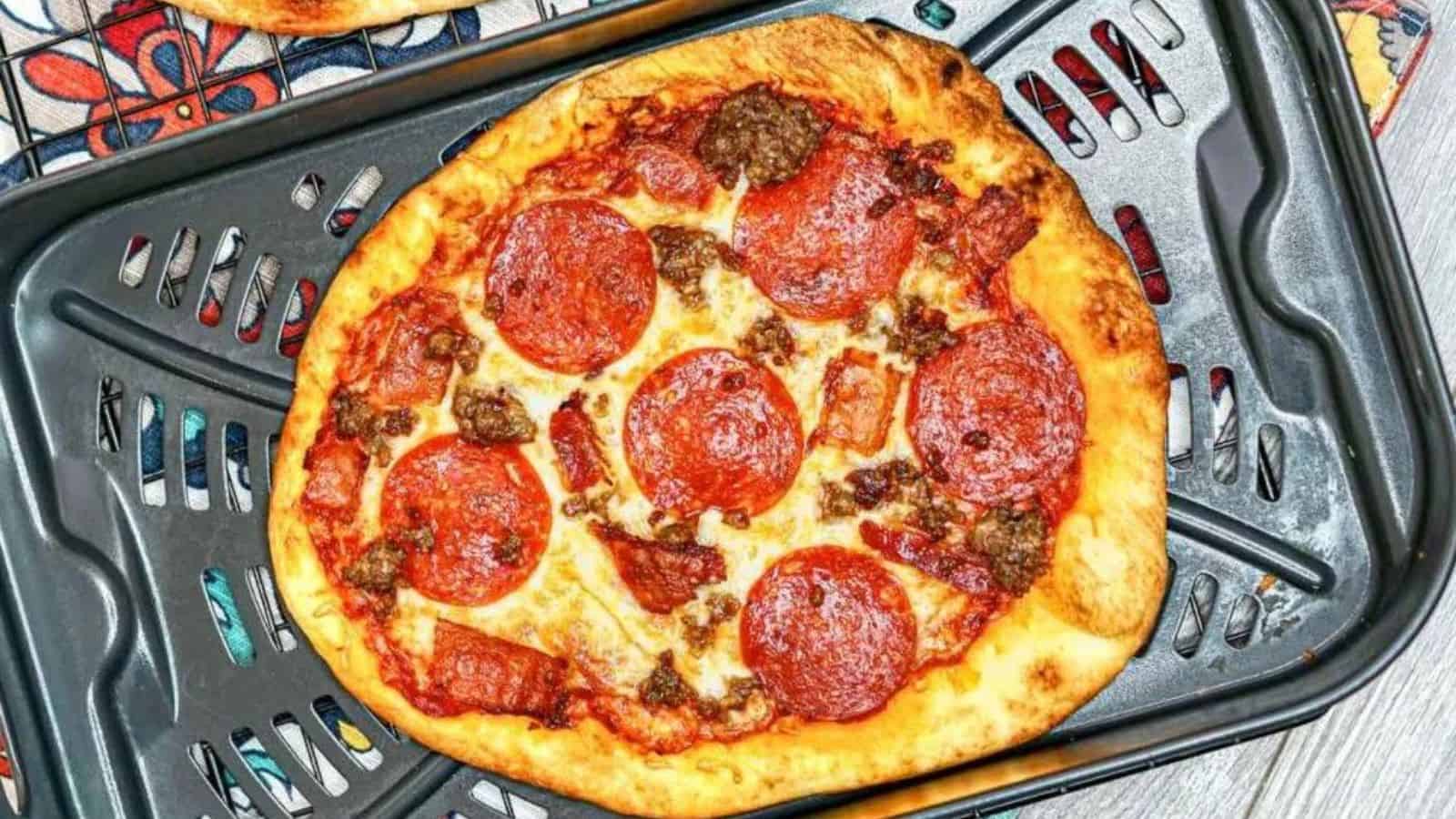 Meat lover&rsquo;s flatbread pizza with various toppings, served on a white plate.