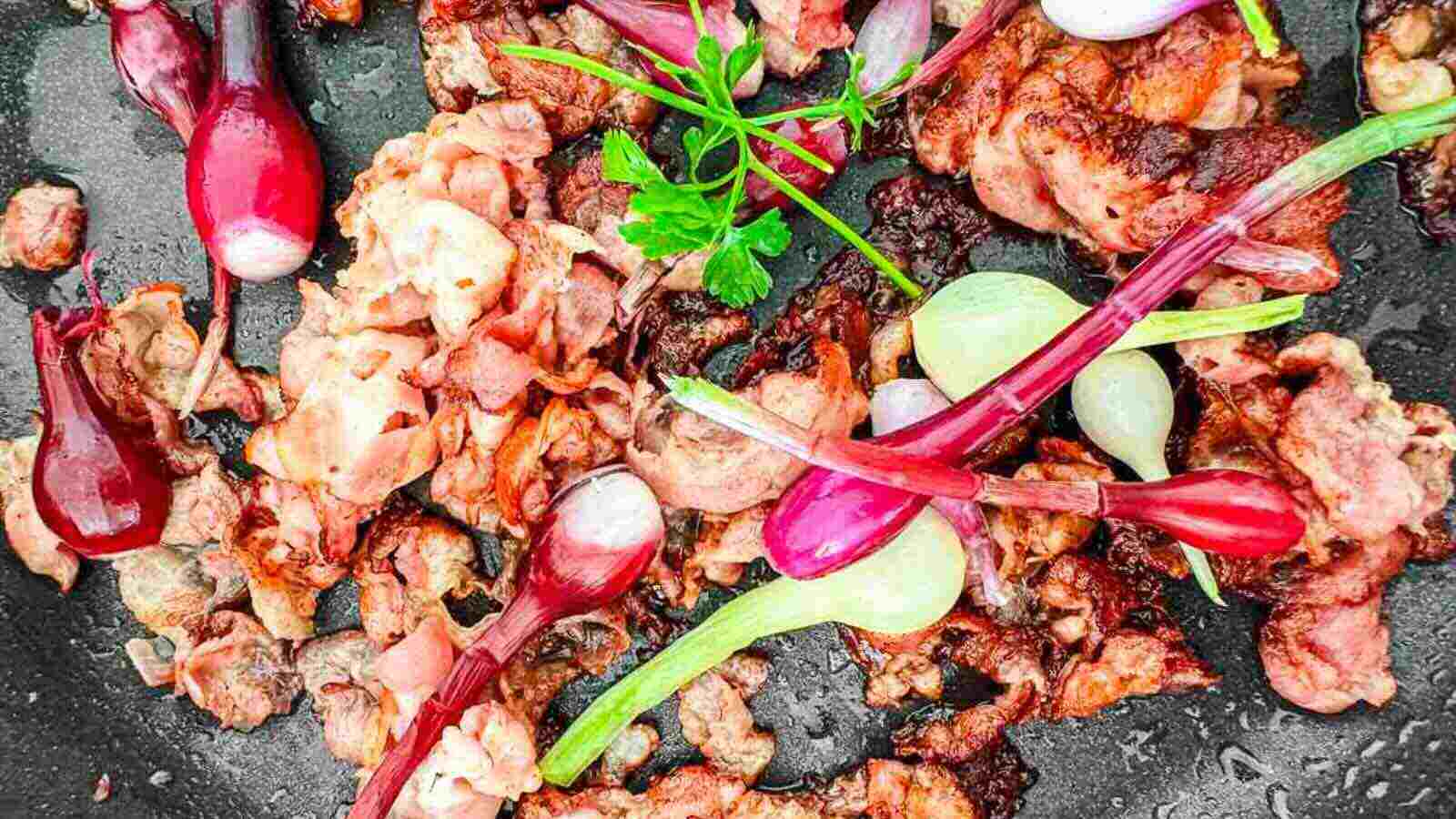 Sizzling pieces of bacon in a frying pan.