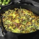 A casserole with brussel sprouts topped with cheese.