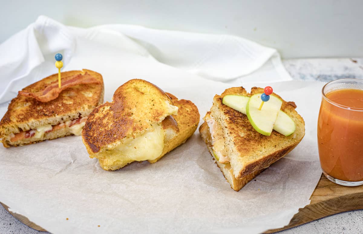 Three grilled cheese flight sandwich halves on parchment paper.