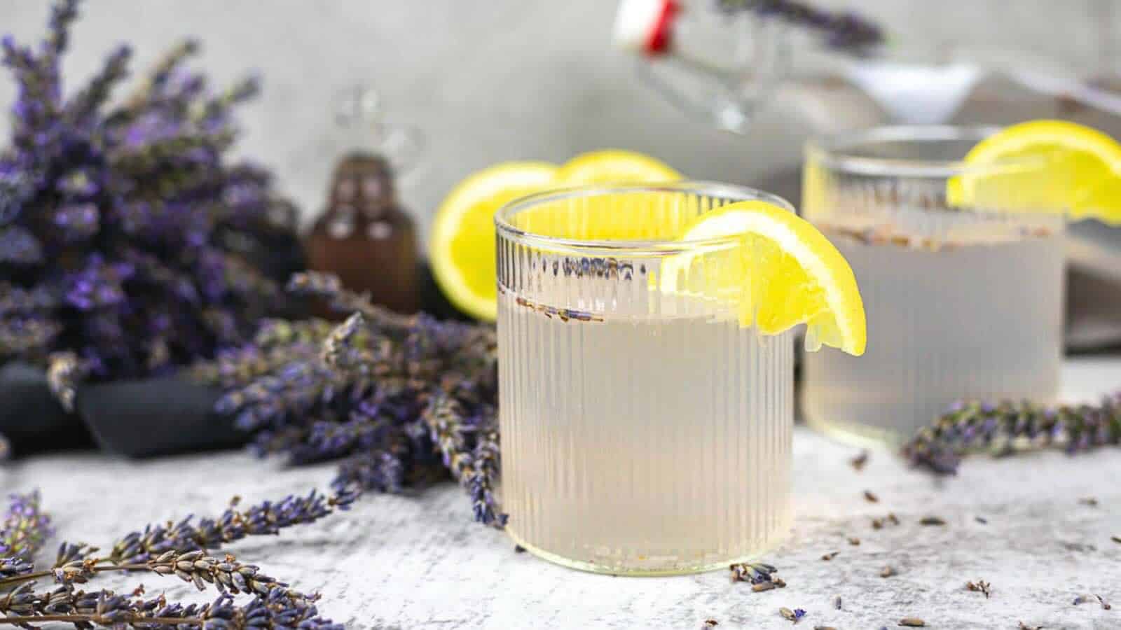 Two glasses of lavender lemonade are garnished with lemon slices.