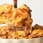 Close-up of a cheese-filled pie with a slice being lifted out, showing the melted cheese stretching from the remaining pie in a white pie dish.