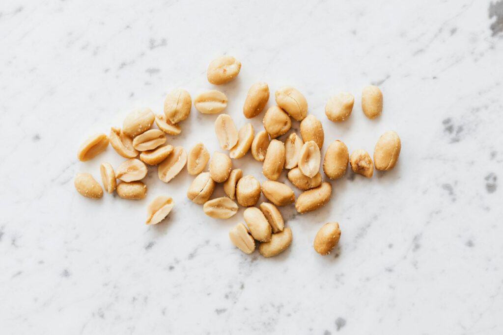 A pile of salted peanuts scattered on a marble surface.