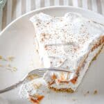 A slice of no-bake pumpkin cheesecake delight on a white plate, partially eaten with a fork resting on the plate.