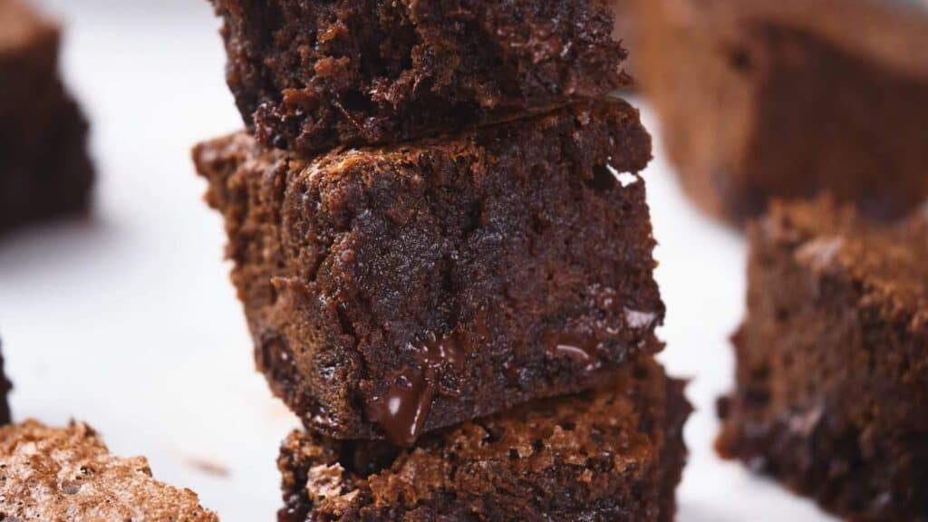 Close-up of a stack of three pumpkin brownies with a rich, moist texture and chunks of melted chocolate.