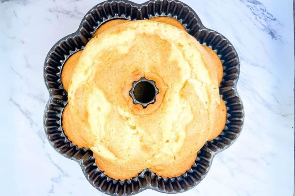 A bundt cake in a shaped pan on a marble surface.