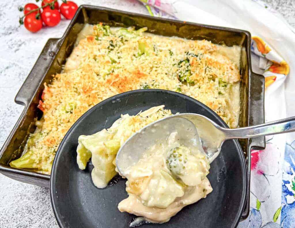 A serving of Turkey Divan from a baking dish onto a black plate.