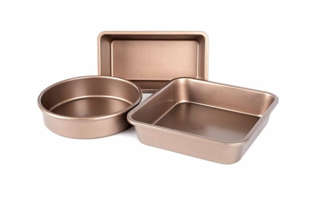 Three golden-brown non-stick baking pans: one round, one square, and one rectangular.