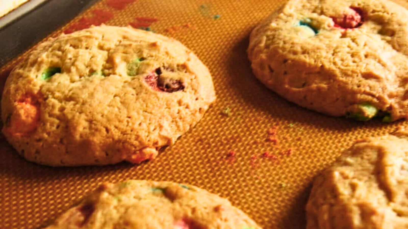 Cookies with colorful candy pieces on a baking sheet.