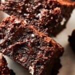 Close-up of several rich, chocolate brownies, featuring a fudgy texture and sprinkled with coarse sea salt on top.