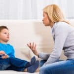 A woman and a young boy sit on a couch, engaged in conversation.