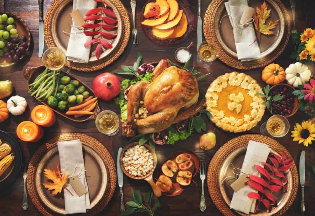 Thanksgiving table setting with a stress-free cooking approach: roast turkey, pumpkin pie, fruits, vegetables, candles, and fall-themed decorations.