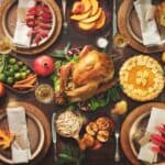 Thanksgiving table setting with a stress-free cooking approach: roast turkey, pumpkin pie, fruits, vegetables, candles, and fall-themed decorations.