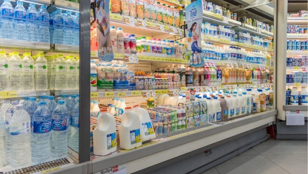 Grocery store refrigerated section filled with various dairy products and bottled water.