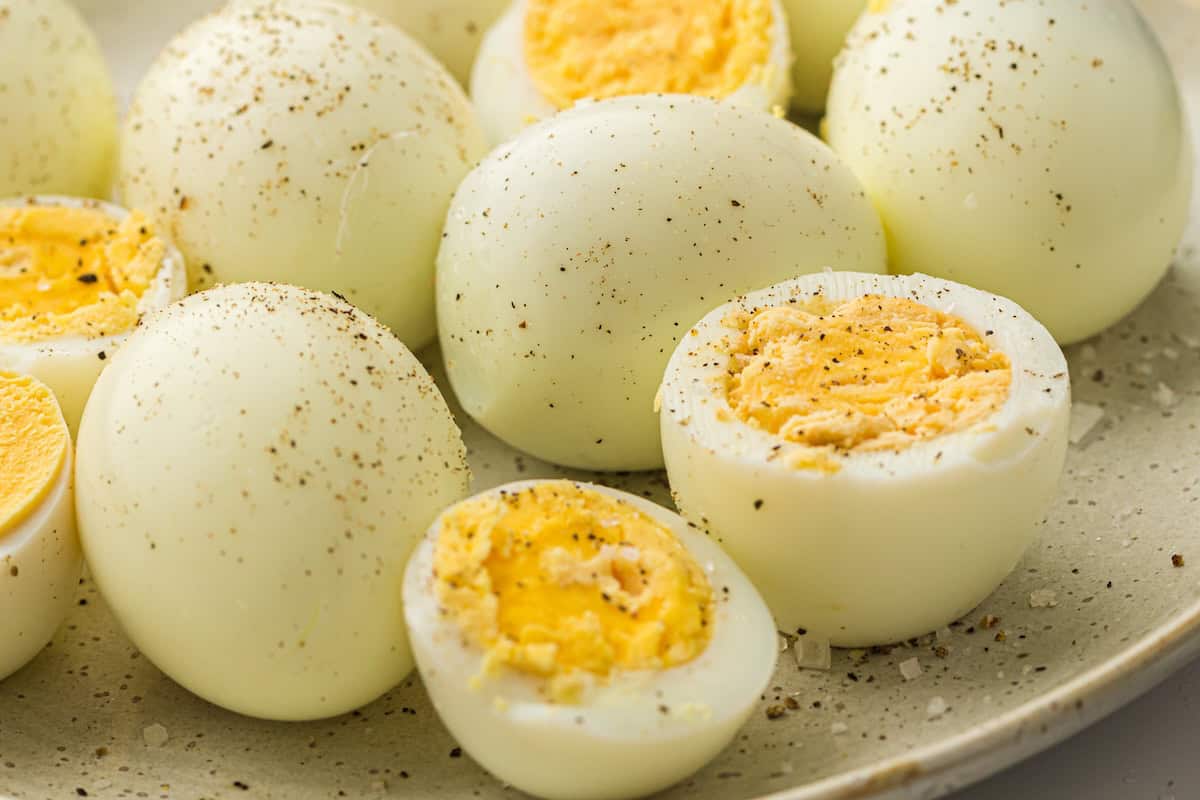 Halved hard-boiled eggs seasoned with salt and pepper on a plate.