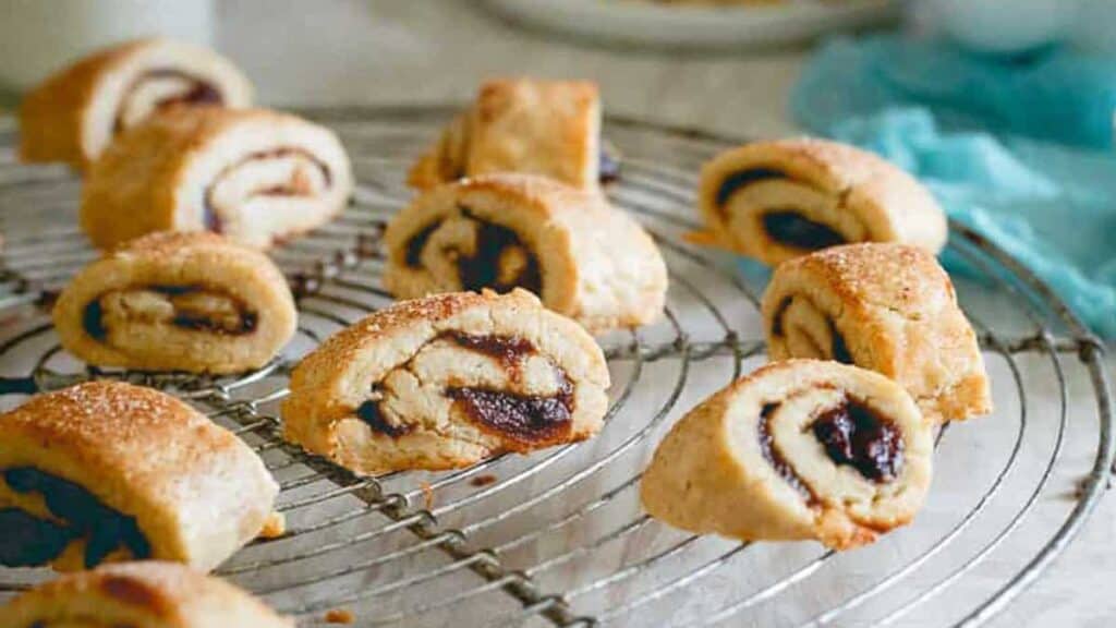 Close-up of sliced pastry rolls with a dark filling, arranged on a cooling rack.