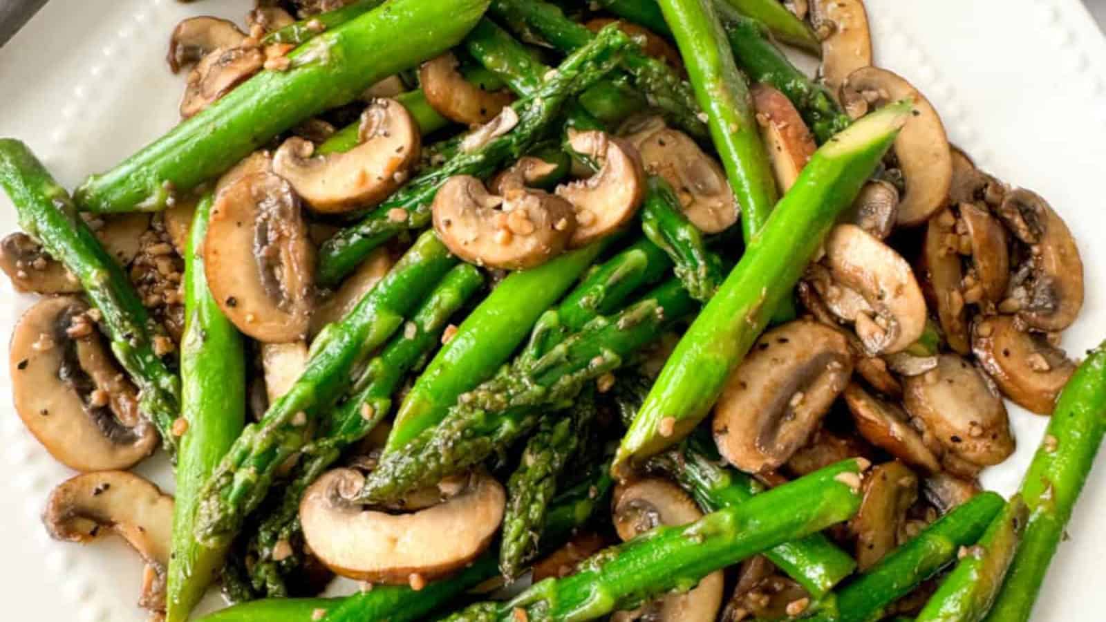 Sauteed asparagus and mushrooms on a white plate.