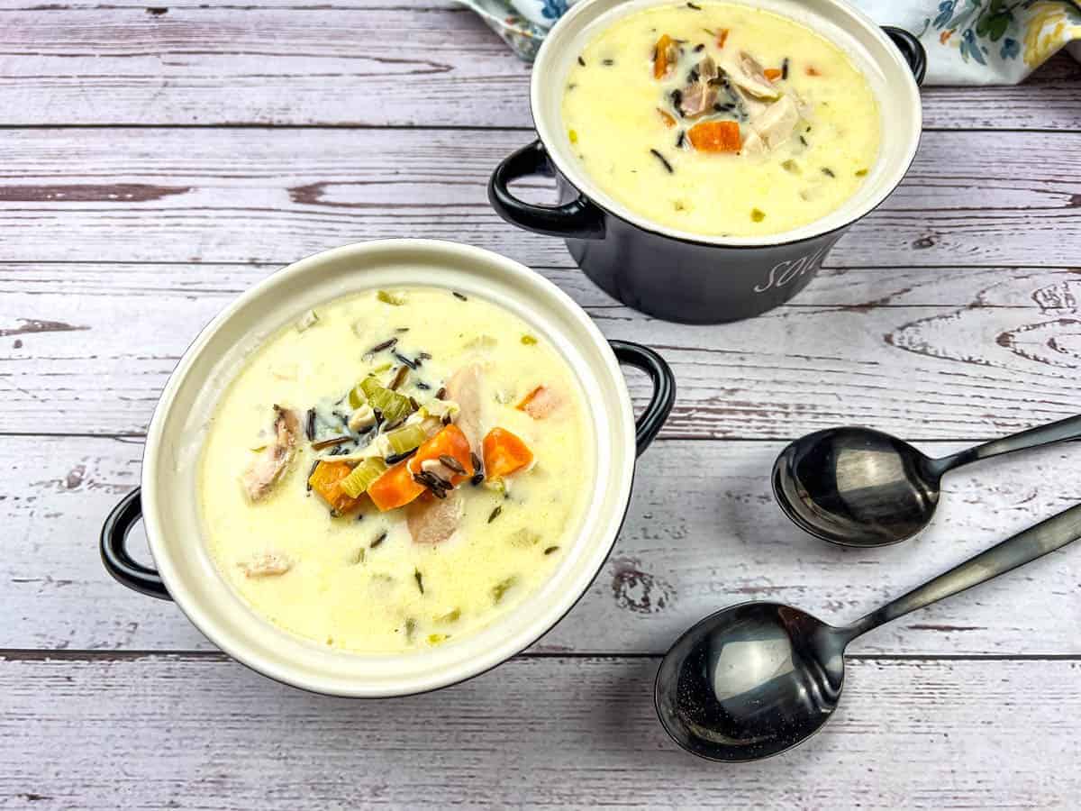 Two bowls of Creamy Turkey & Wild Rice Soup accompanied by two spoons.